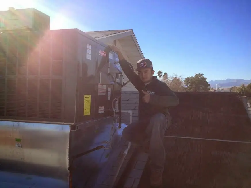HVAC technician performing AC Tune-Up on a rooftop unit in Harrietstown