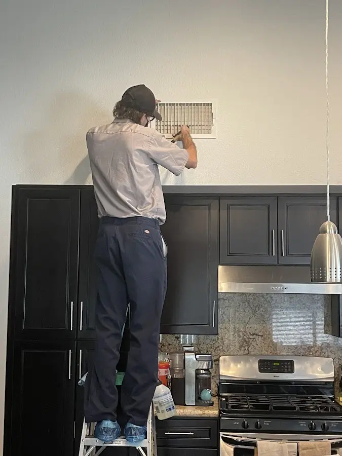 Technician inspecting an air vent during HVAC service in Harrietstown
